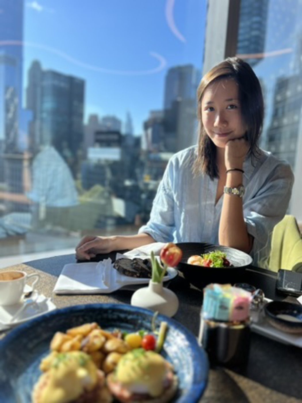 Warm window-lit brunch portrait with NYC skyline