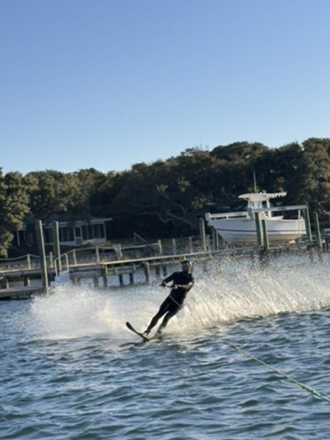 Waterskier carving a spray across a calm bay past a docked boat