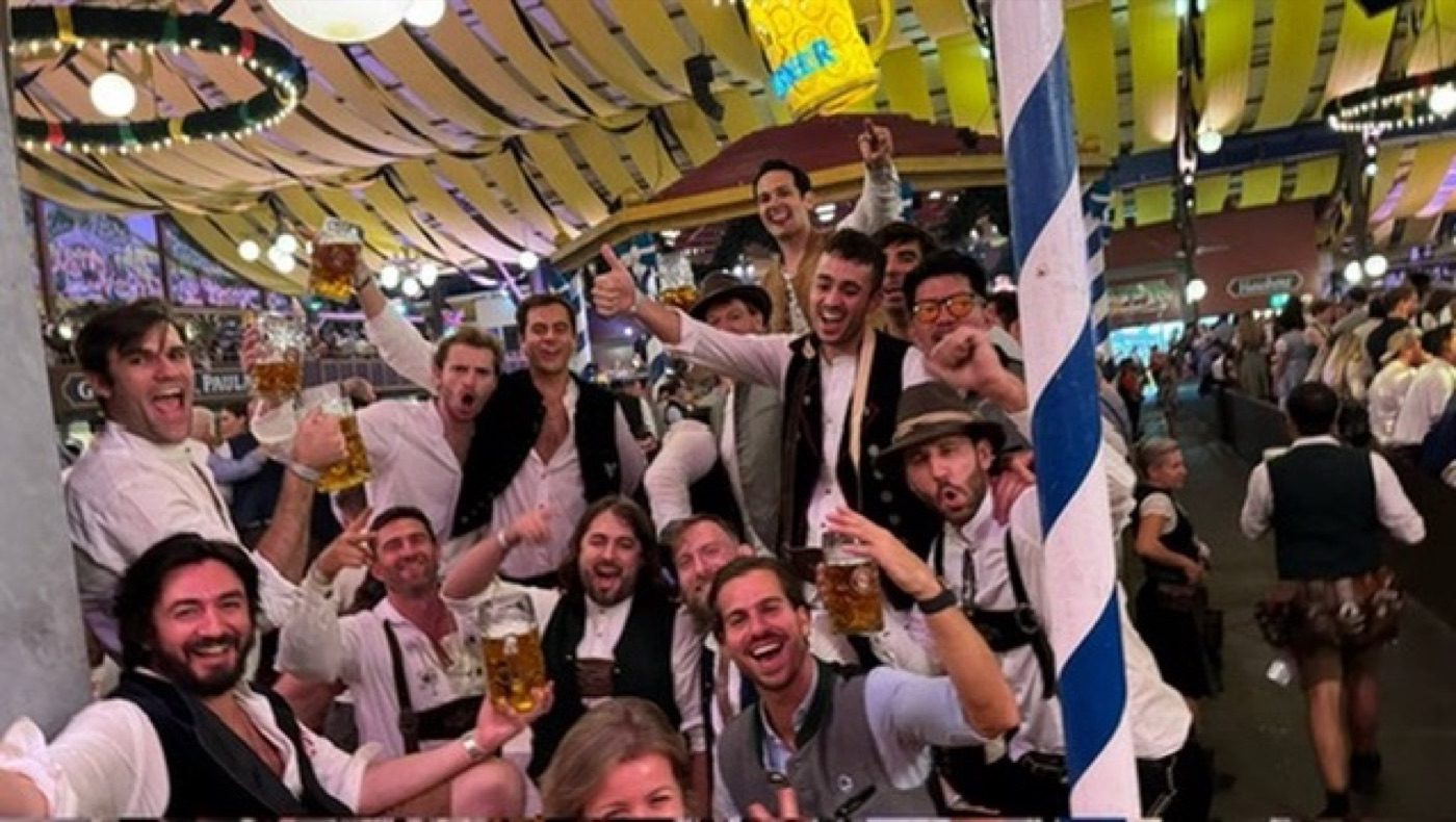 Cheerful crowd raising beer steins in a decorated Oktoberfest tent