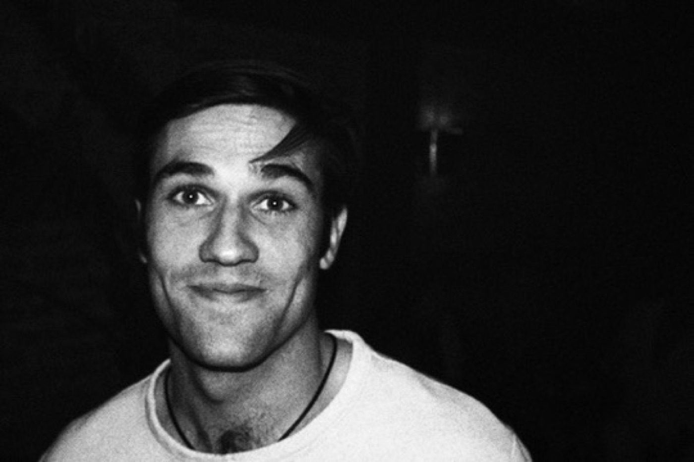 Black-and-white candid close-up with a playful half-smile