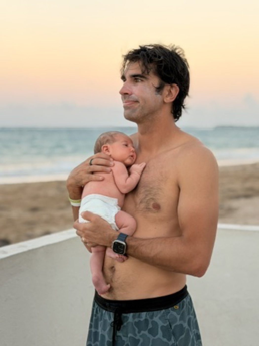 Beach-sunset moment holding a sleeping newborn