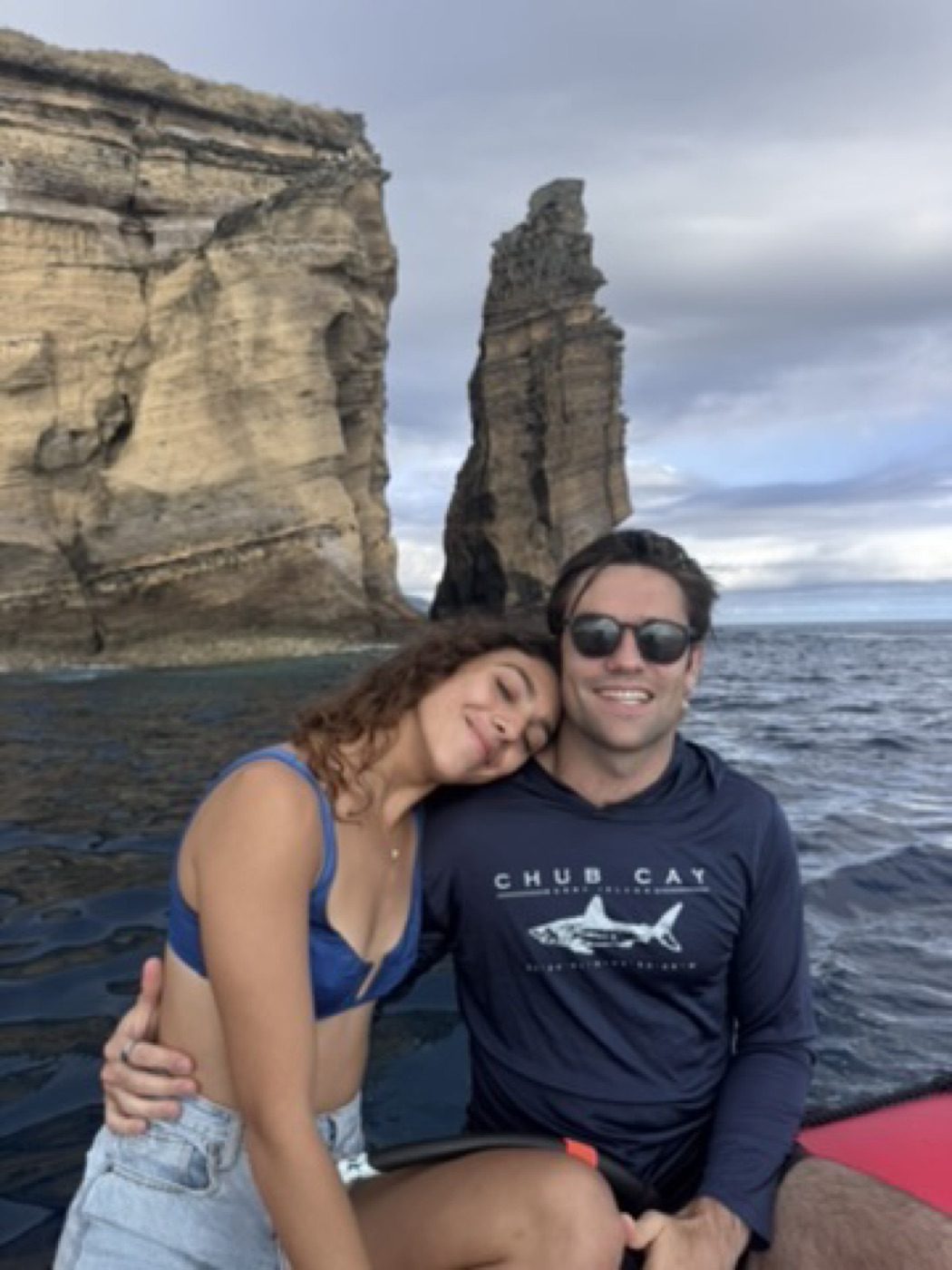 Cheek-to-cheek couple on a boat, ocean stack behind