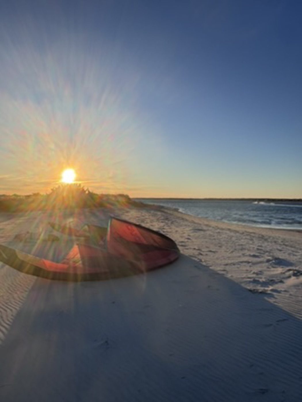 Sunburst over a beached boat with lens-flare rays