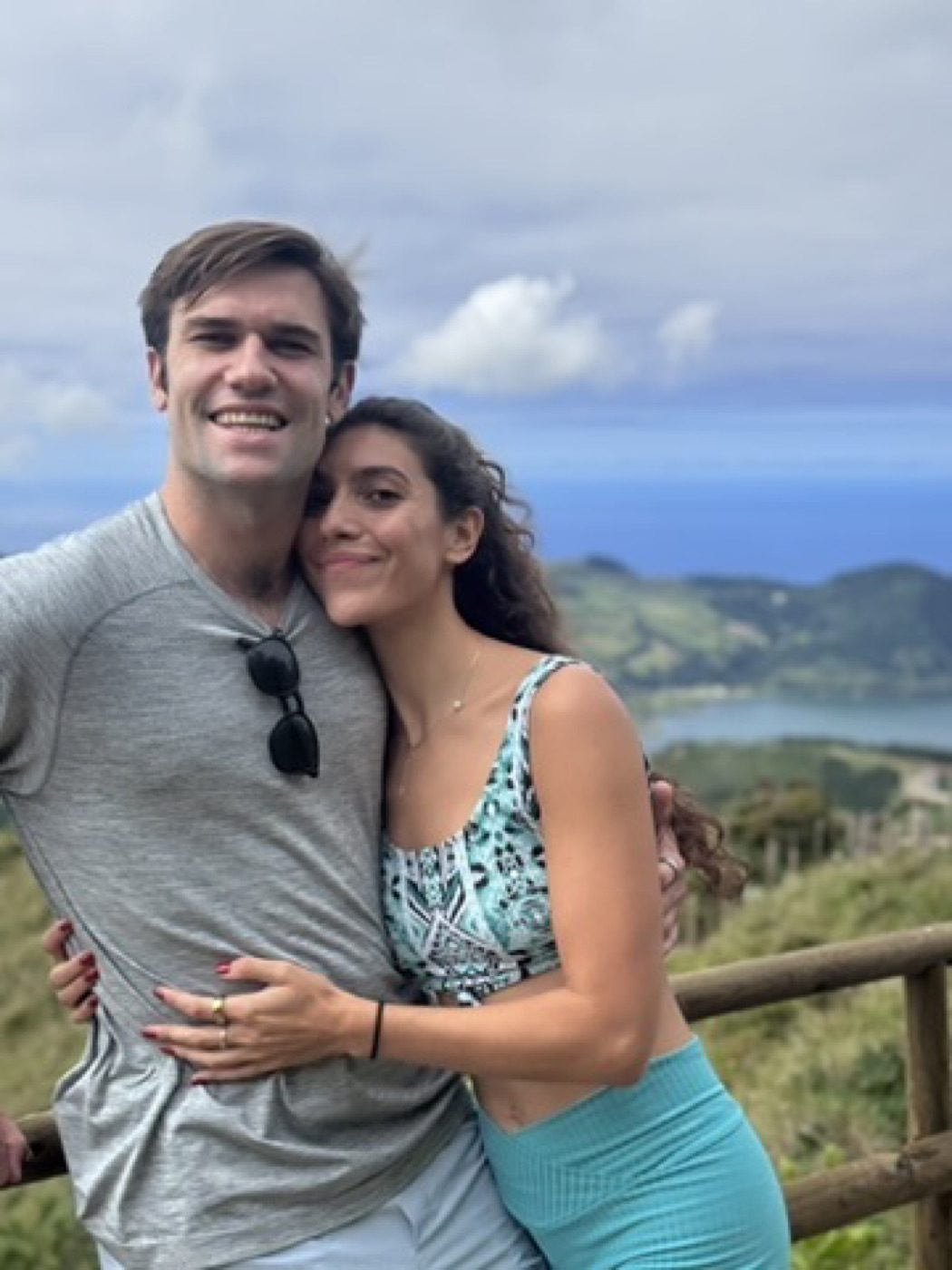 Warm couple embrace overlooking the ocean, both beaming