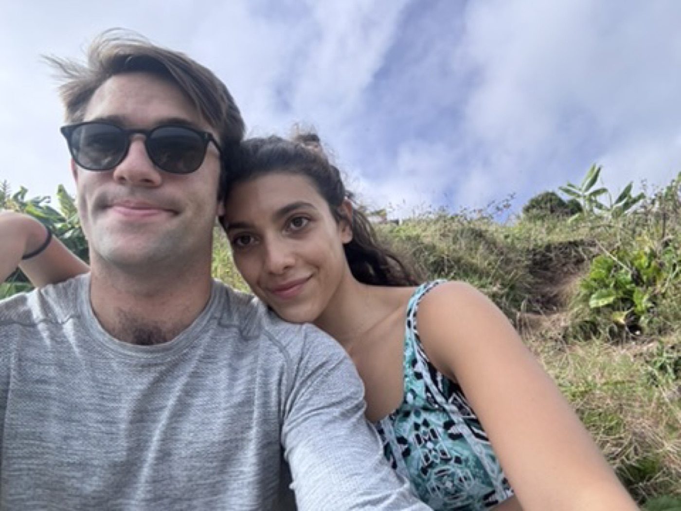 Cozy cheek-to-cheek couple resting on a grassy hillside