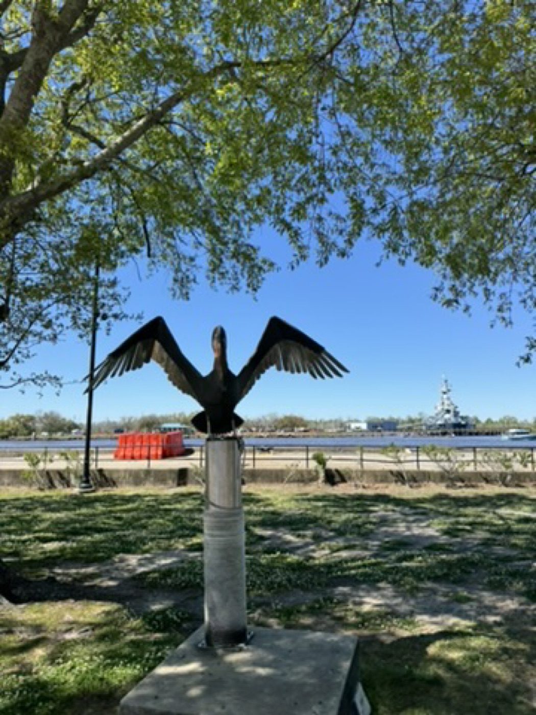 Pelican statue with wings spread against blue sky