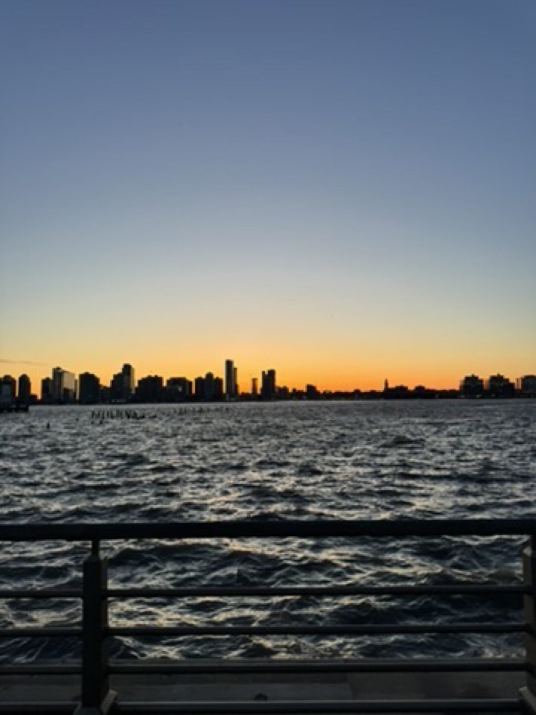 Golden dusk skyline silhouette across the rippling Hudson River