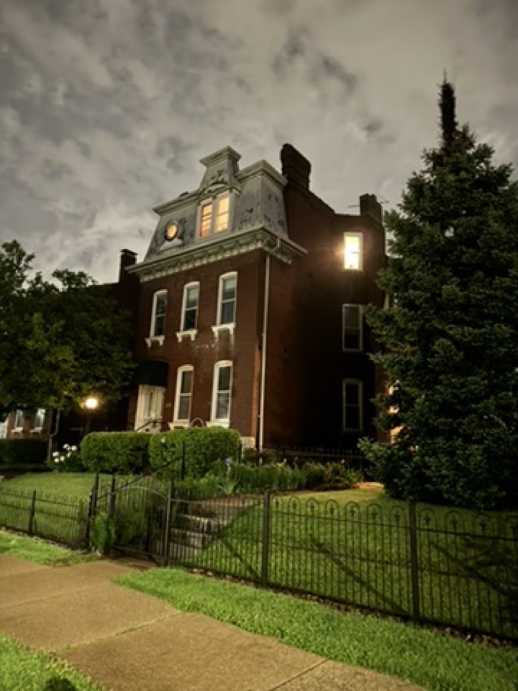 Victorian brick house glowing under a moody clouded night sky