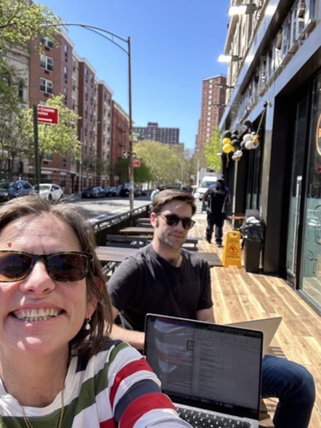 Noel and family laughing at a sunny NYC sidewalk cafe