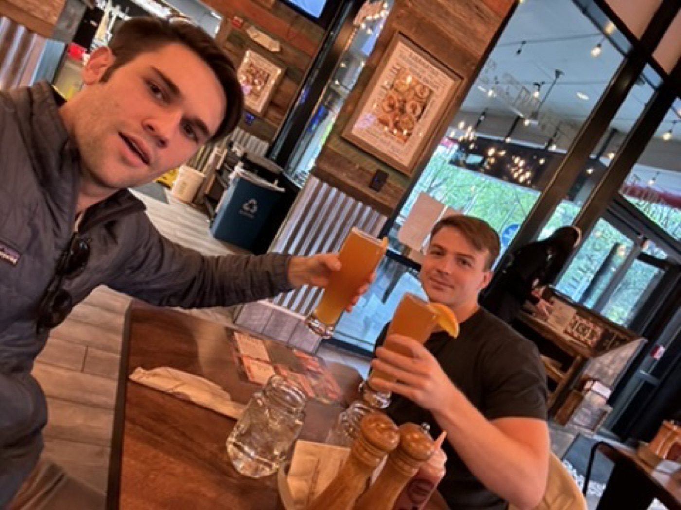 Cheers-ing tall beers with a buddy at a lively bar