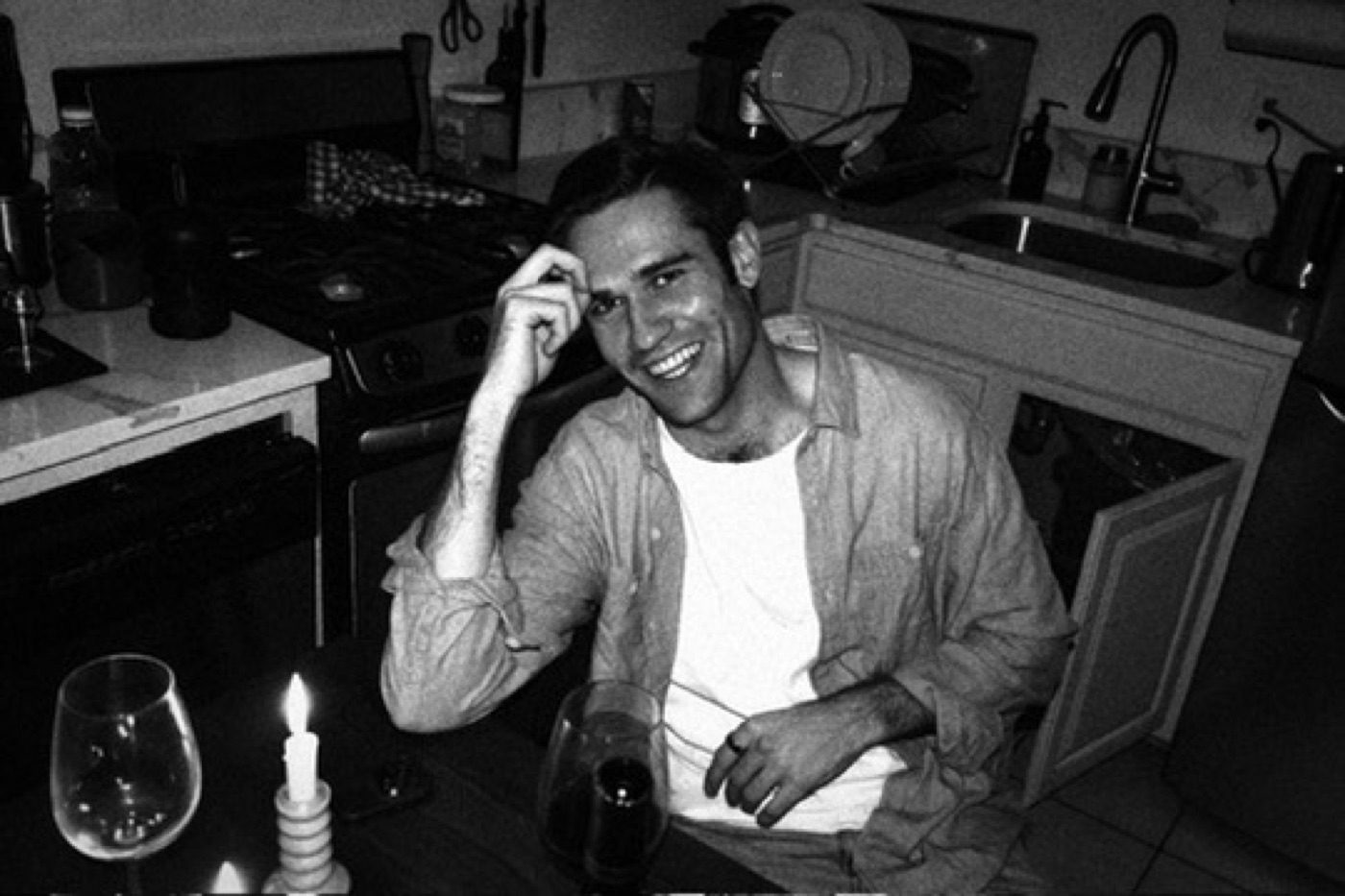 Black-and-white candid of a laughing man at a candlelit dinner