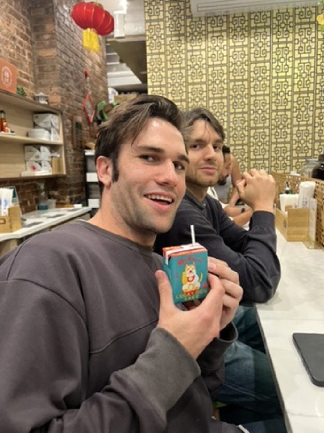 Smiling man holding a juice box at a cozy eatery