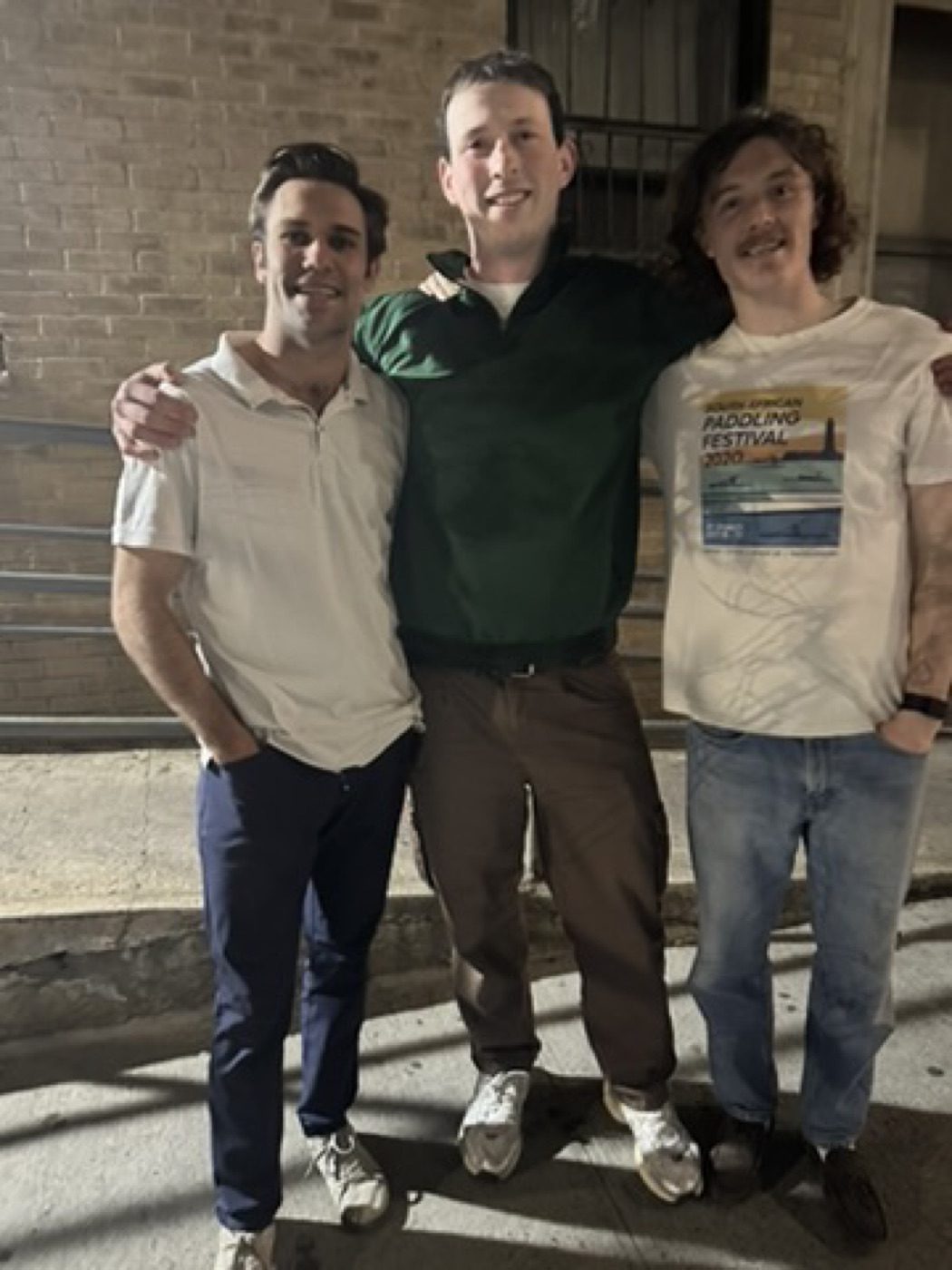 Three friends arm-in-arm posing at night outdoors