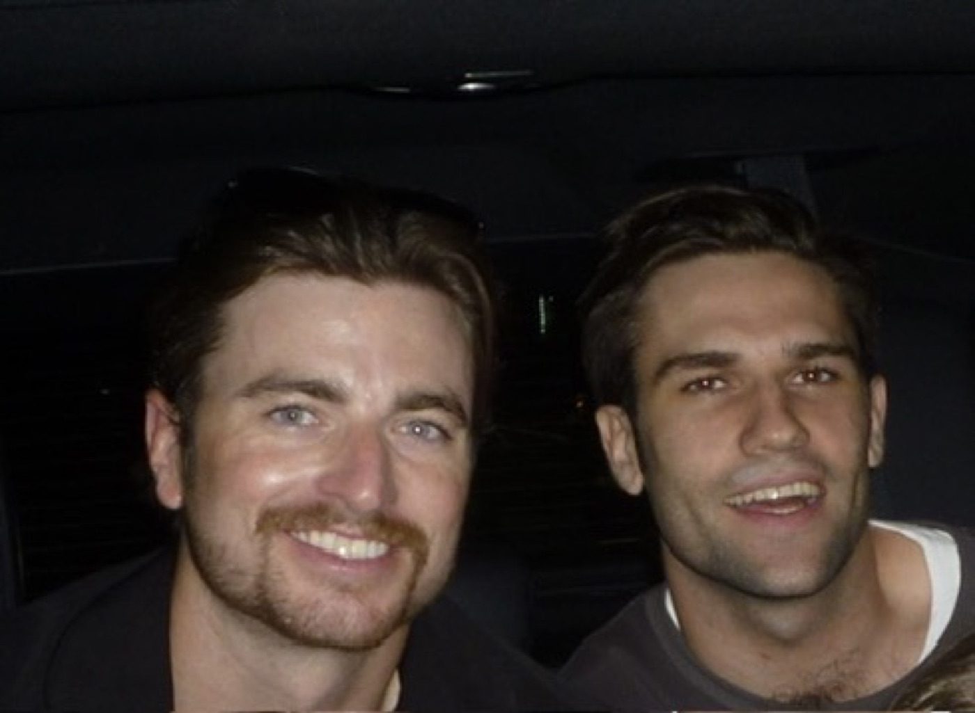 Two men grinning in a nighttime car selfie