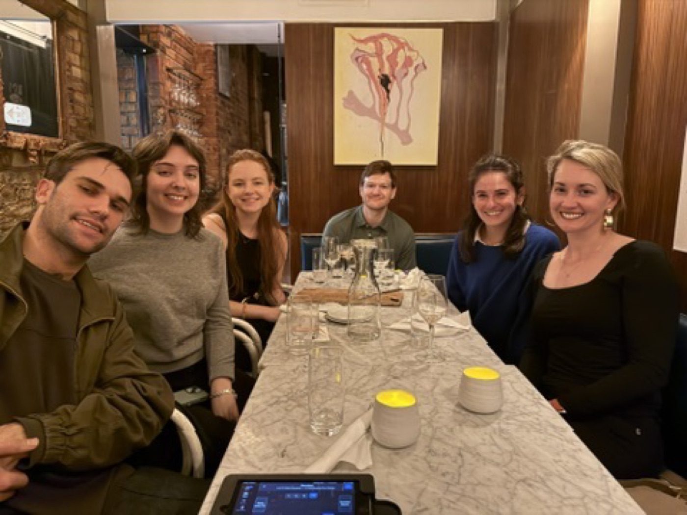 Six friends smiling around a marble restaurant table