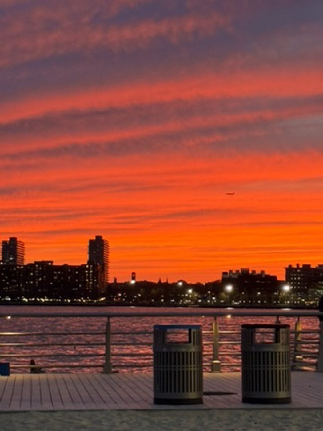 Fiery red-orange sunset over a city waterfront pier