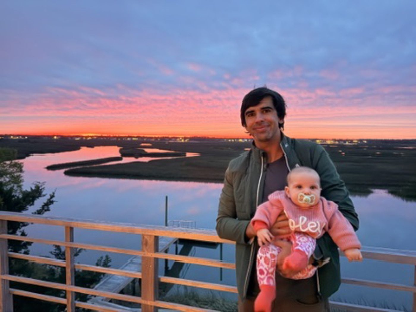 Dad and baby against a vivid pink marsh sunset