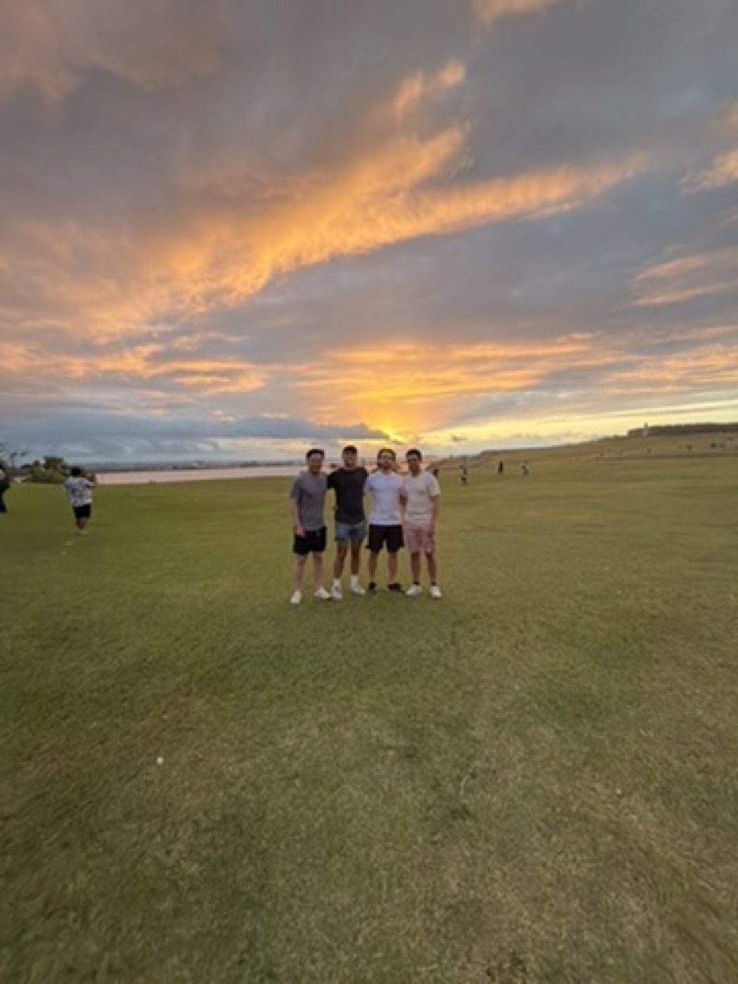Four friends, dramatic golden sunset over water