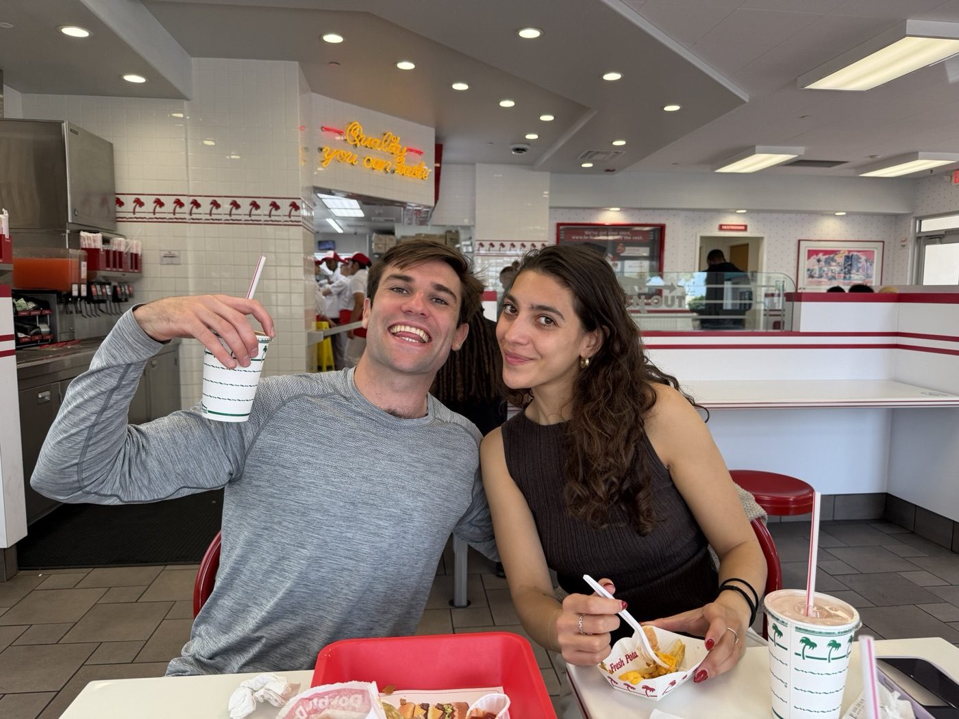 Noel and his partner grinning over burgers at In-N-Out