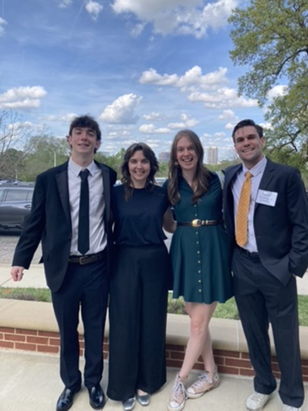 Two couples dressed up and beaming outside an event