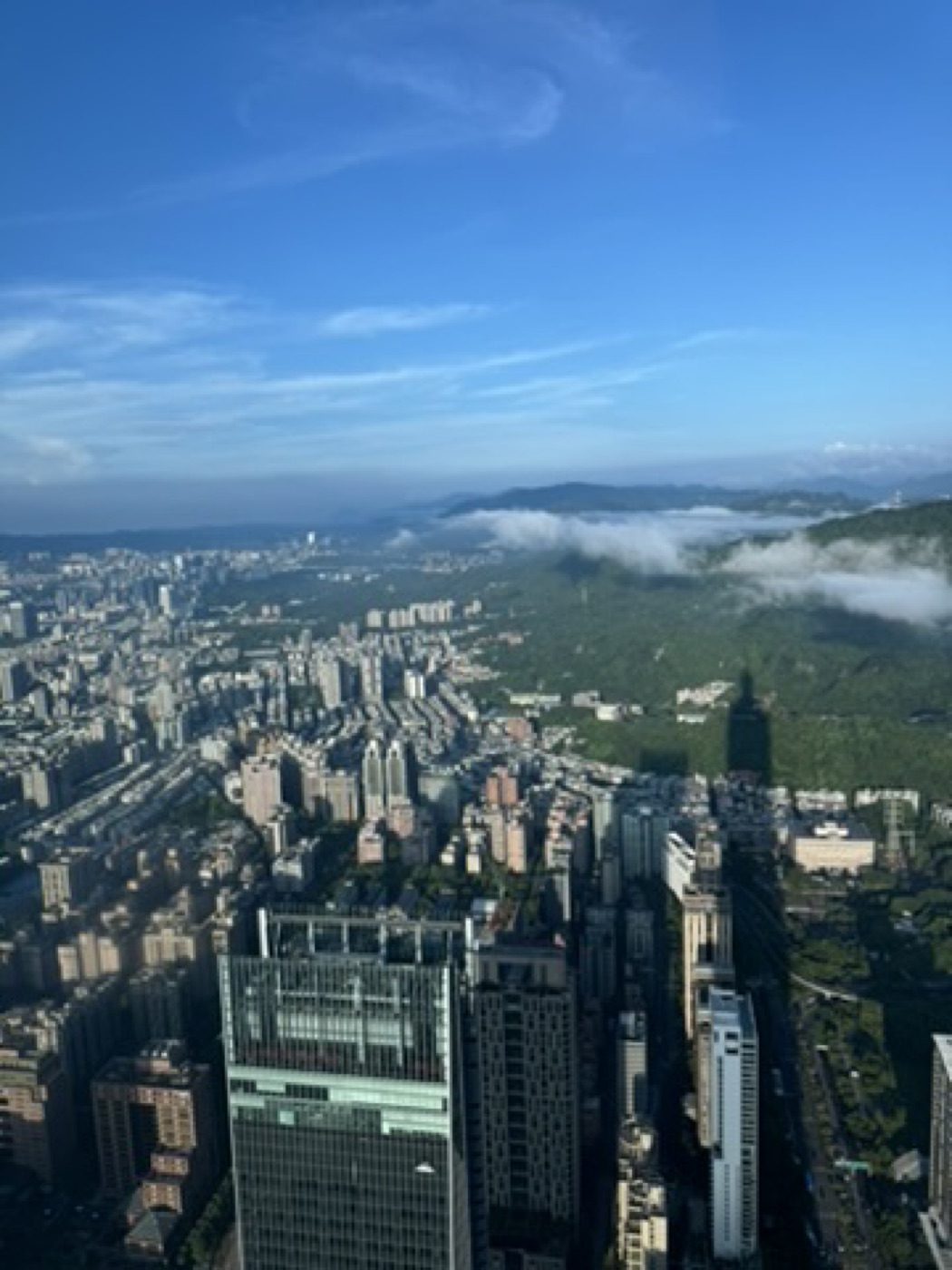 Aerial cityscape, clouds rolling over green mountains