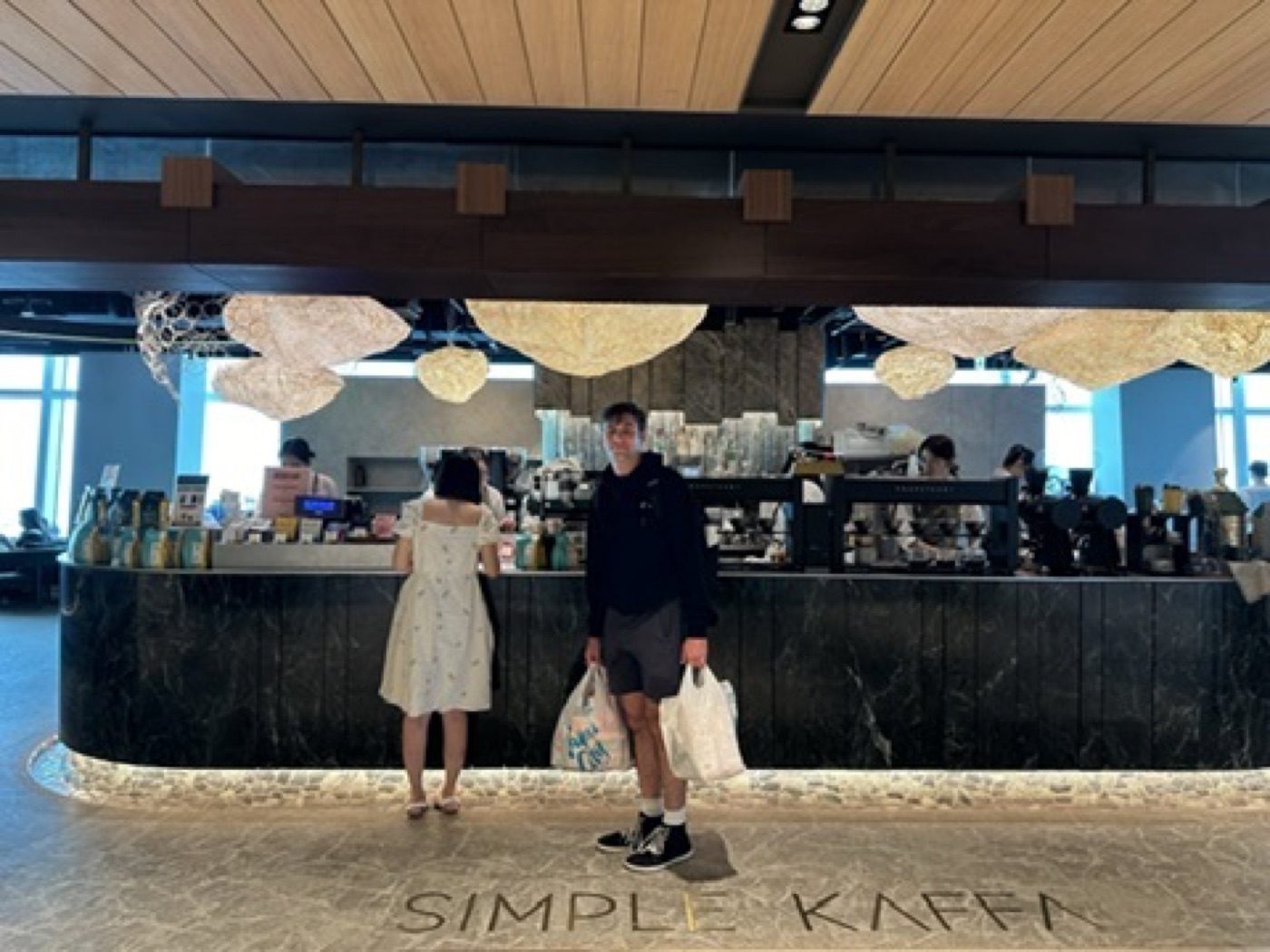 Noel and partner posing with shopping bags at a cafe