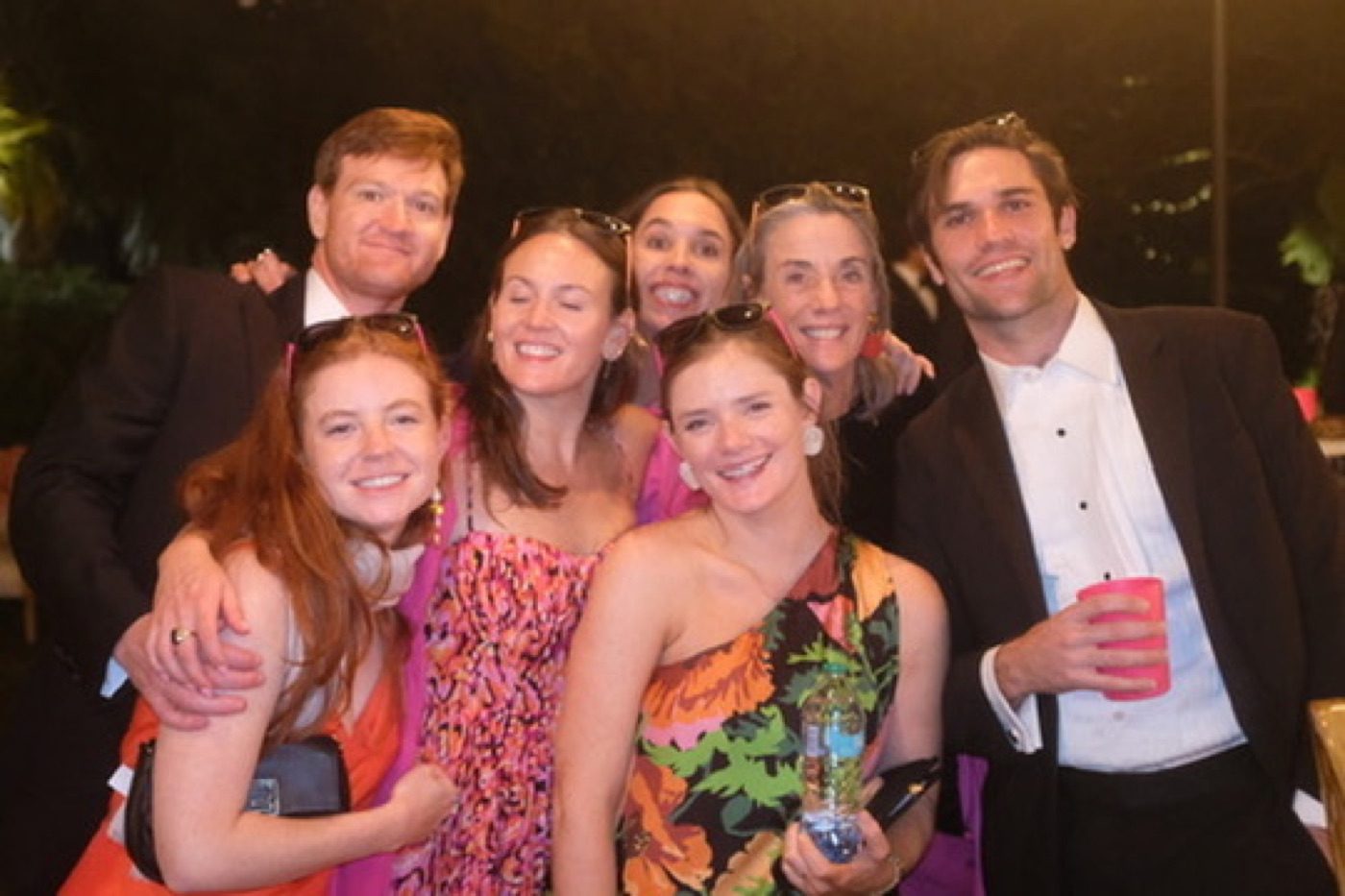 Group of friends laughing at a festive nighttime gala
