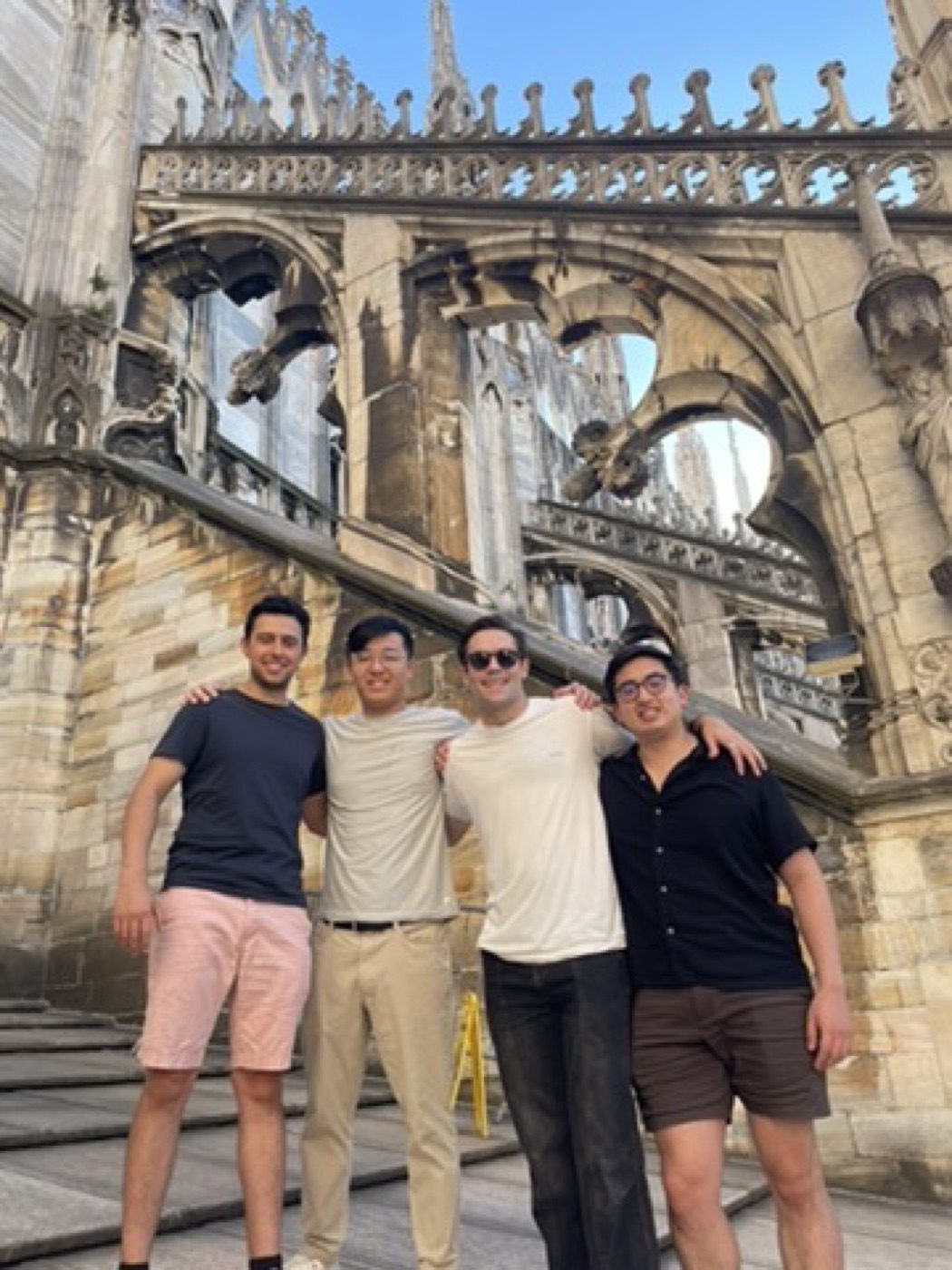 Four friends arm-in-arm on the sunlit Milan Duomo rooftop