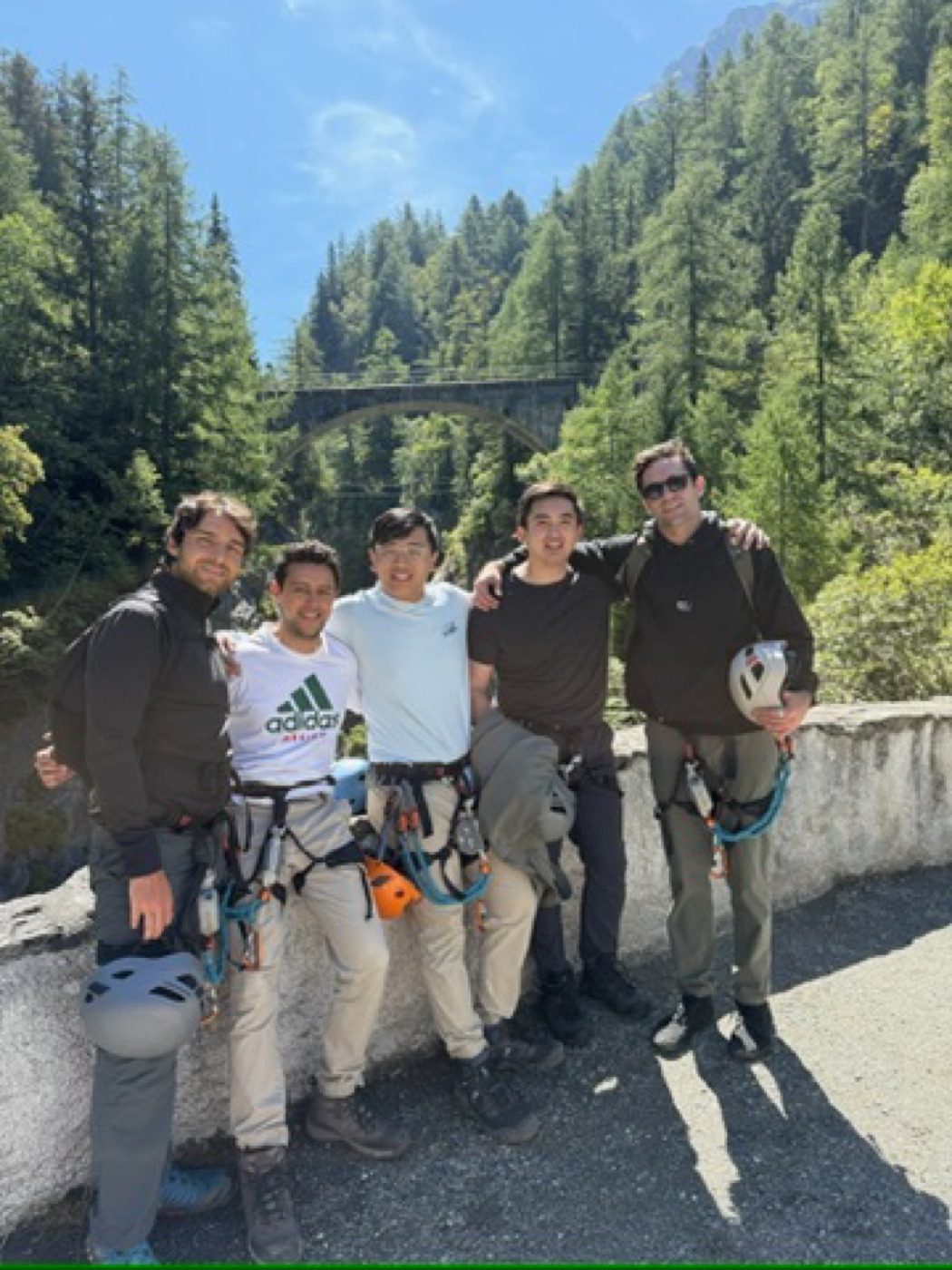 Five friends grinning arm-in-arm after a via ferrata climb
