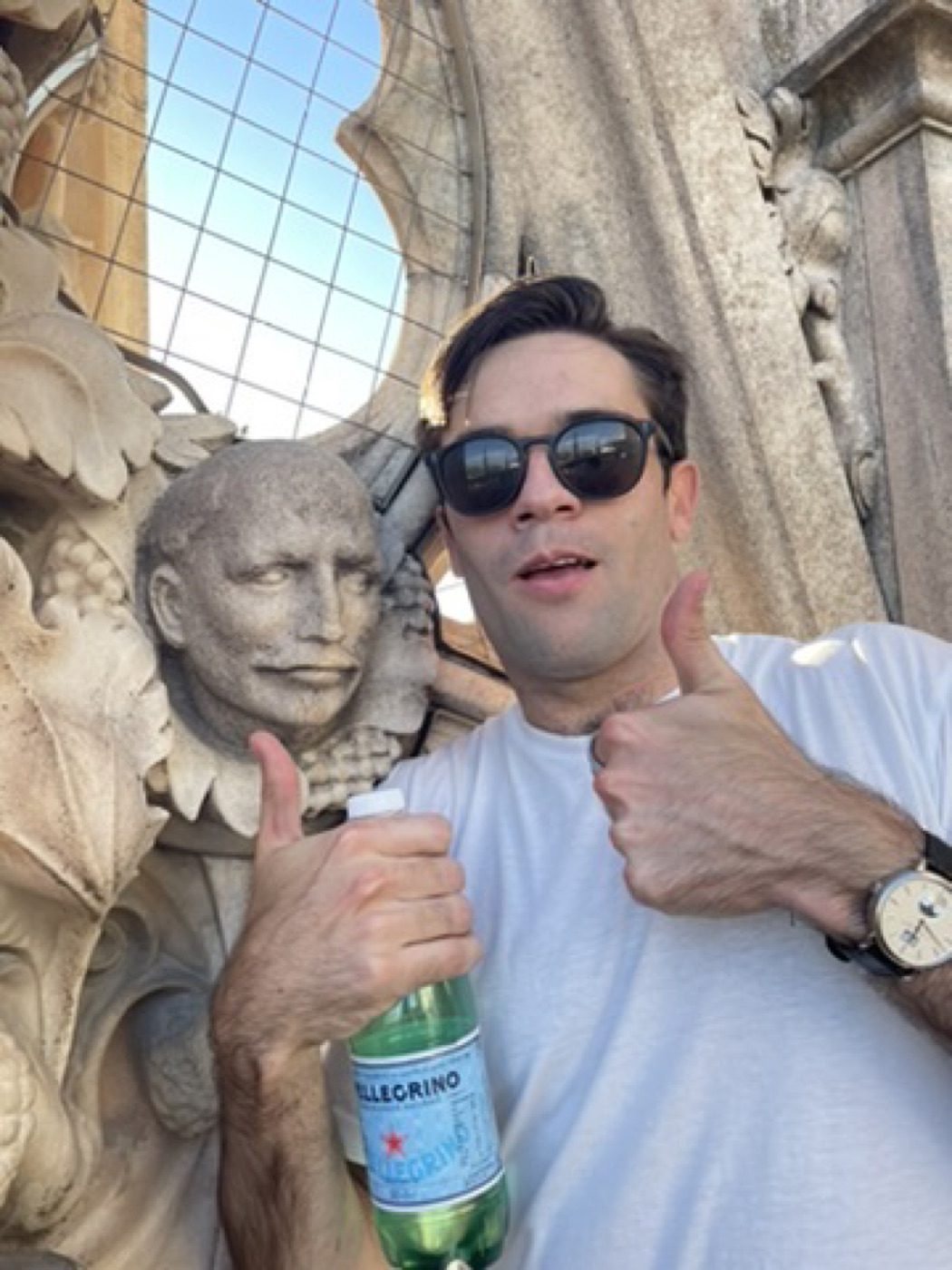 Goofy double thumbs-up with a stone face and Pellegrino