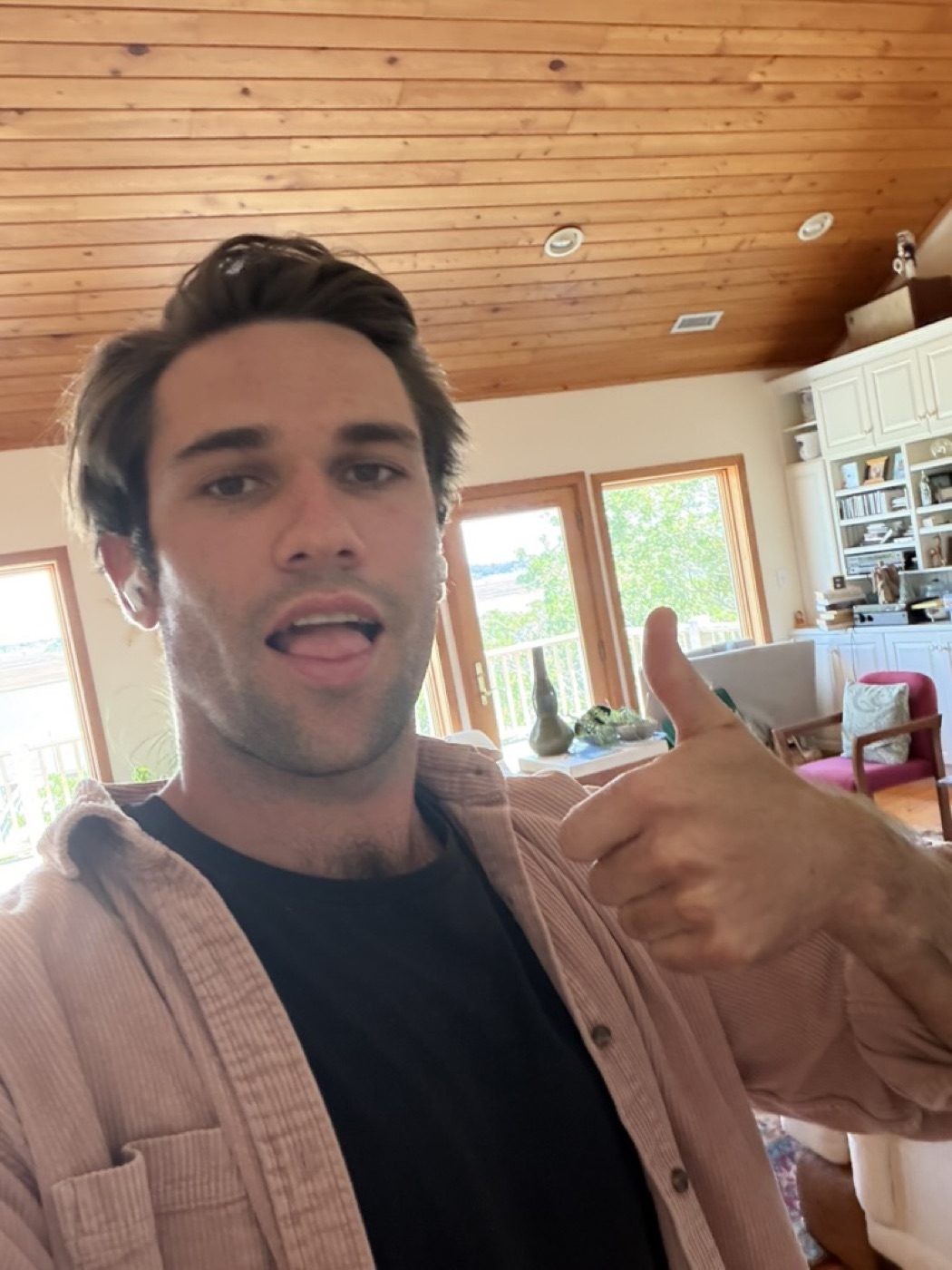 Tongue-out thumbs-up in a sunlit living room