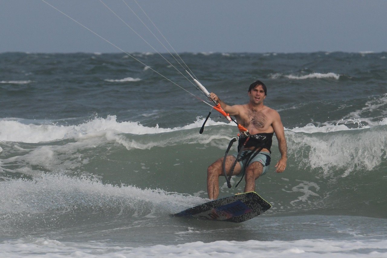 Riding a wave in, kite overhead and grinning