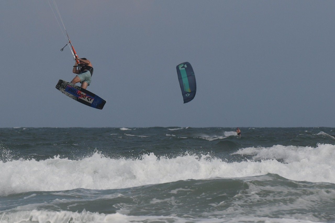 Big air with the board grabbed, a second kite and rider out past the break