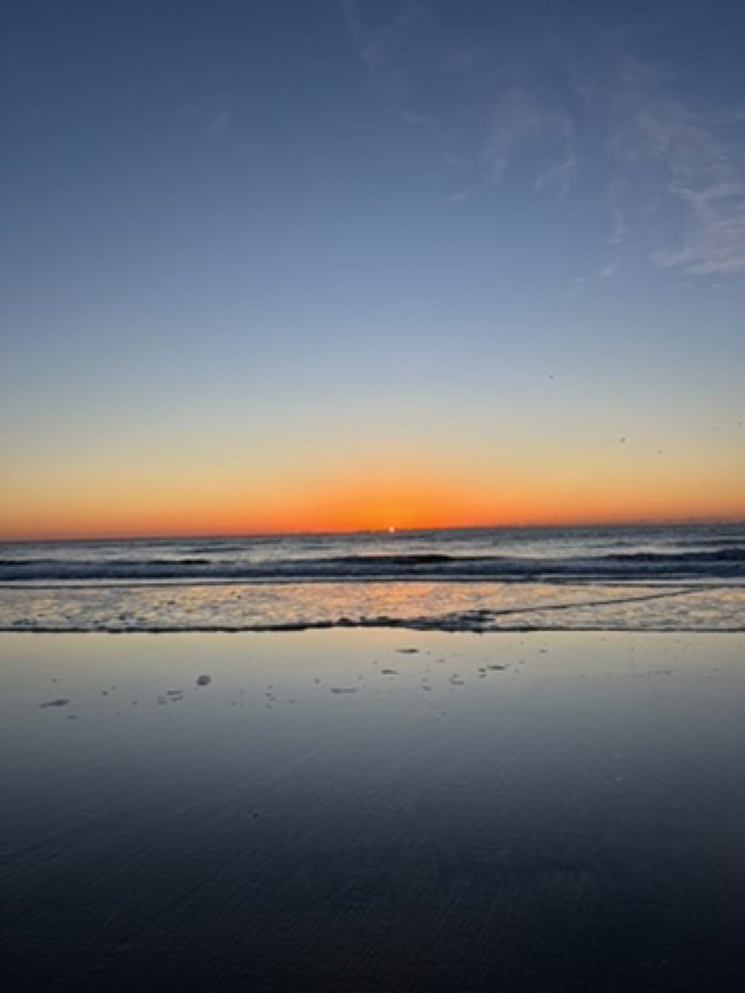 Clean beach sunrise with glowing wet-sand reflection