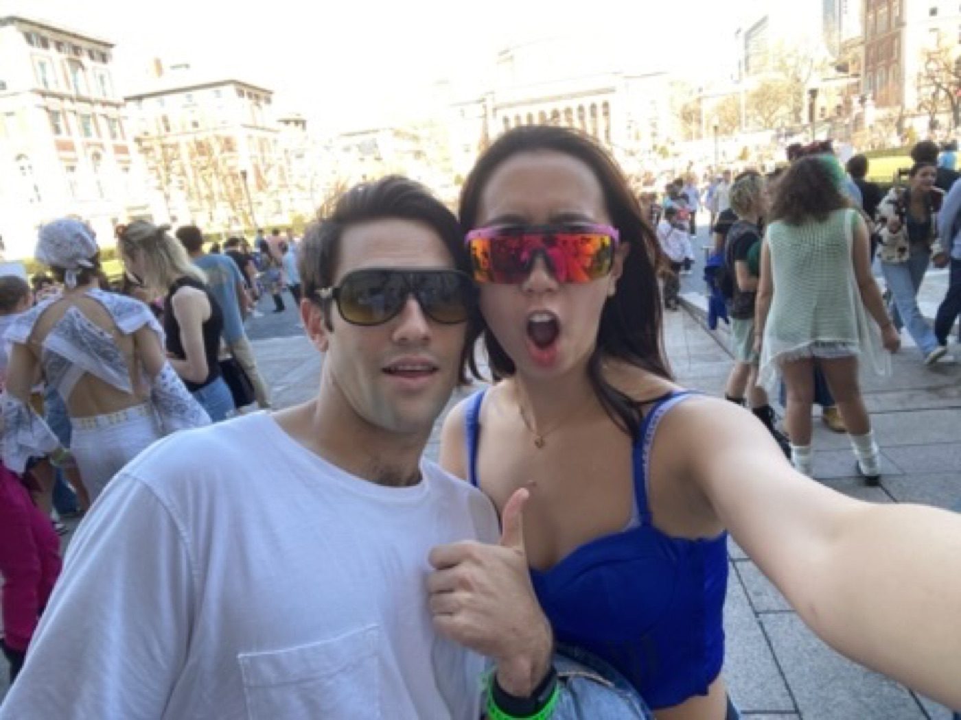 Playful sunglasses selfie with his partner in a festival crowd