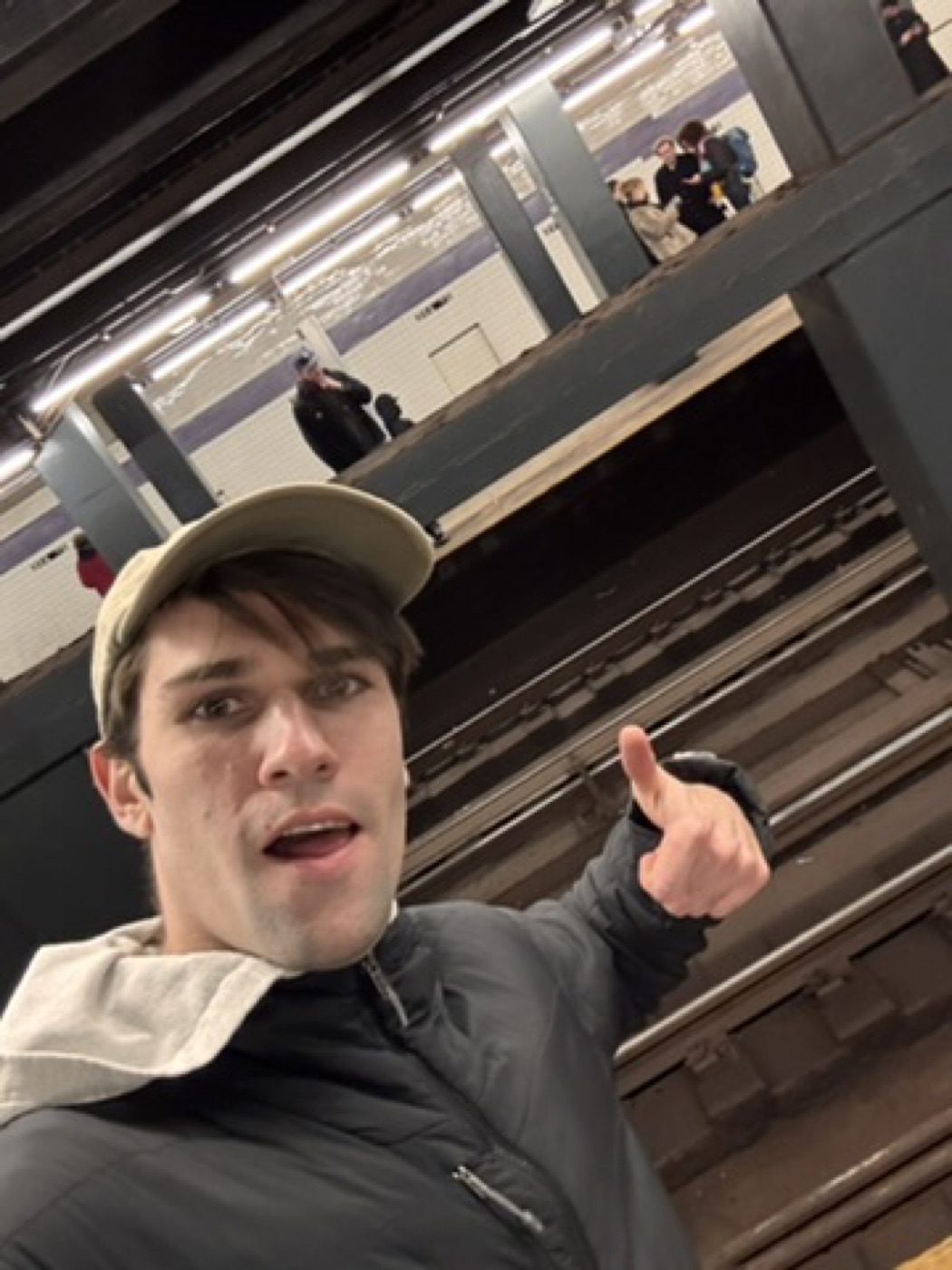 Man giving a thumbs-up selfie on a subway platform