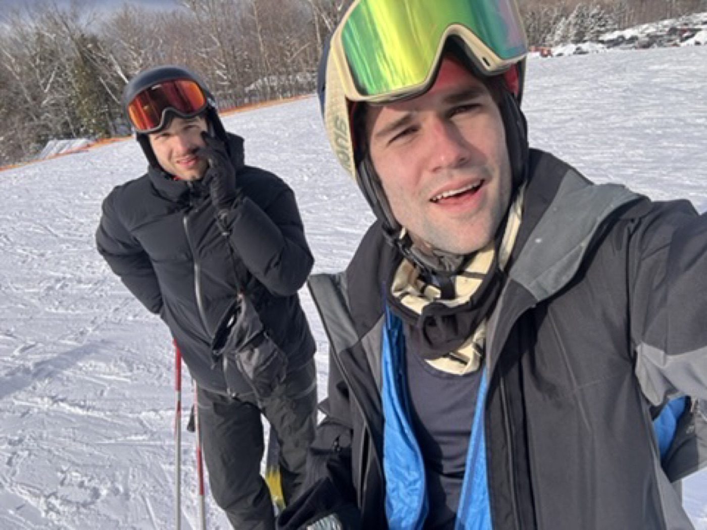 Two buddies grinning on the sunny ski slopes