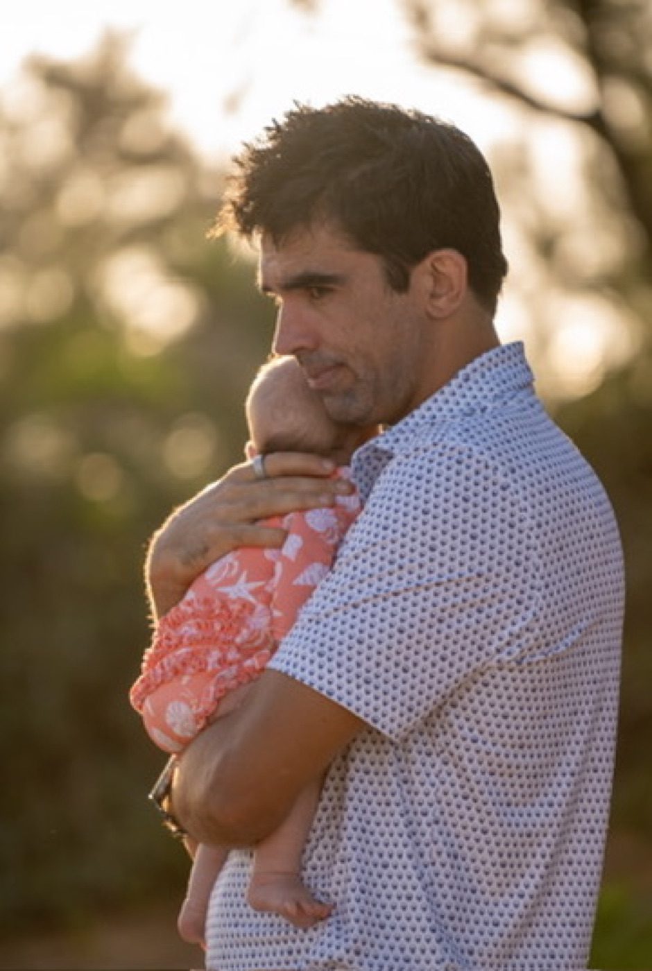 Backlit golden-hour father cradling a baby