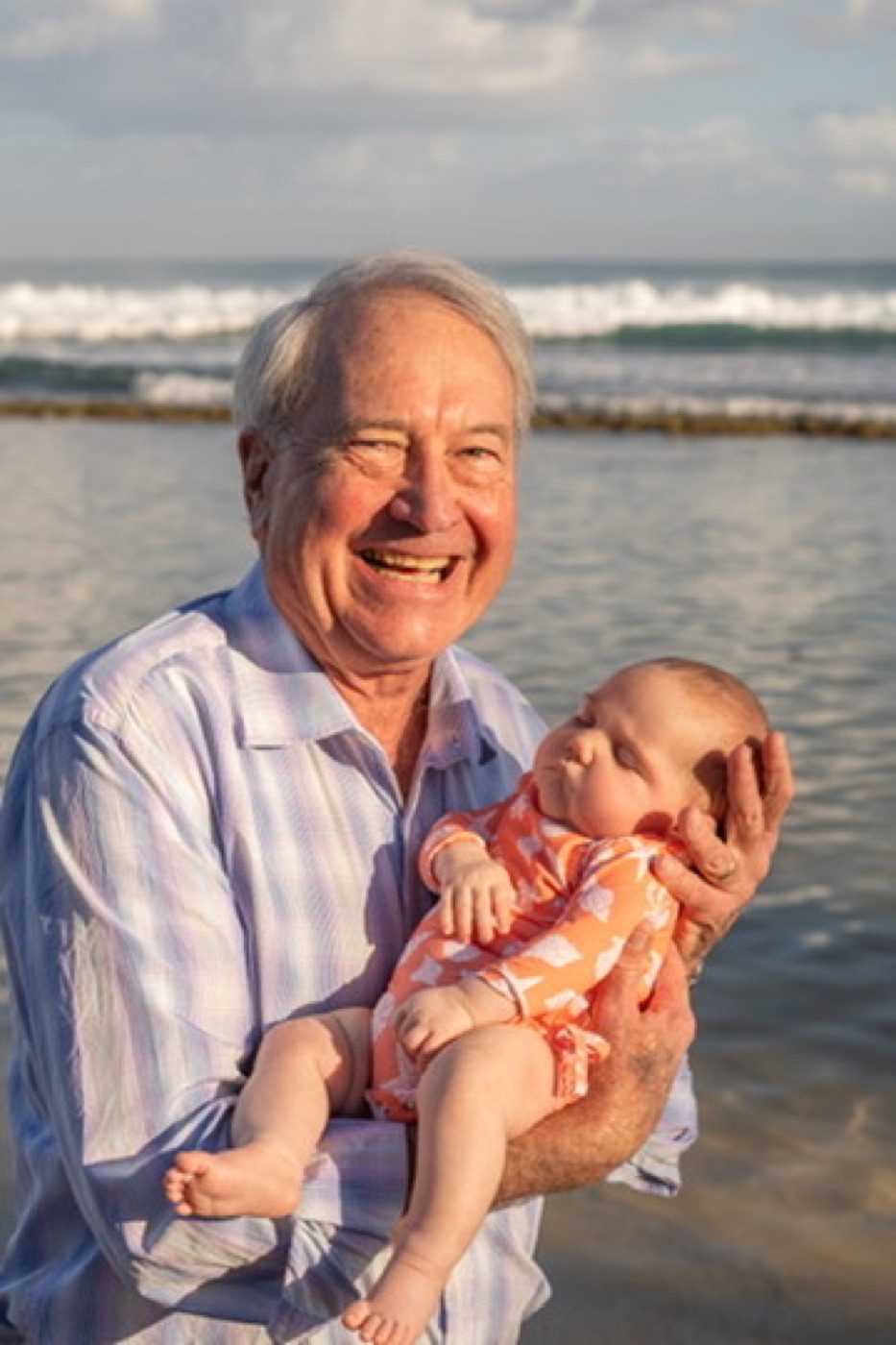 Grandfather beaming with a sleeping baby