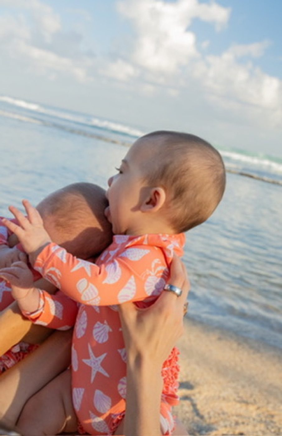 Two babies nuzzling on a sunny beach
