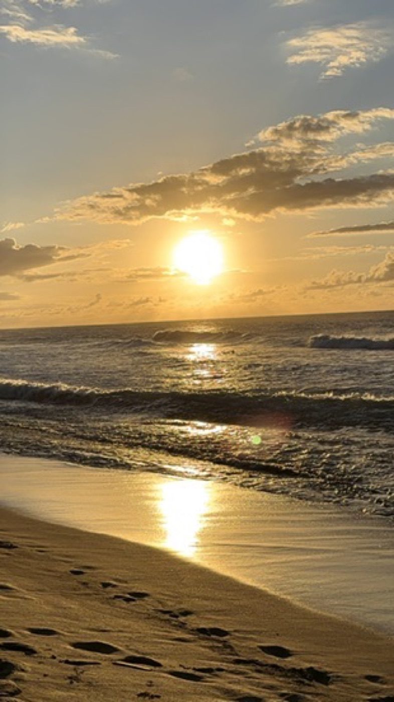 Golden sunrise over surf with footprints