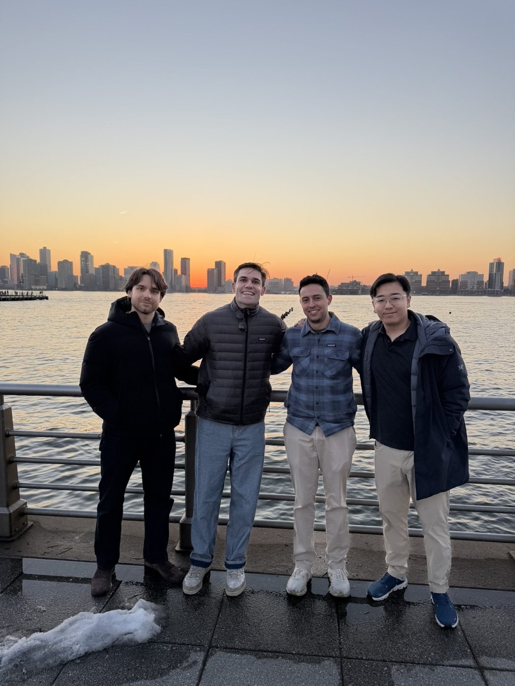 Noel and three friends, arms around, sunset skyline
