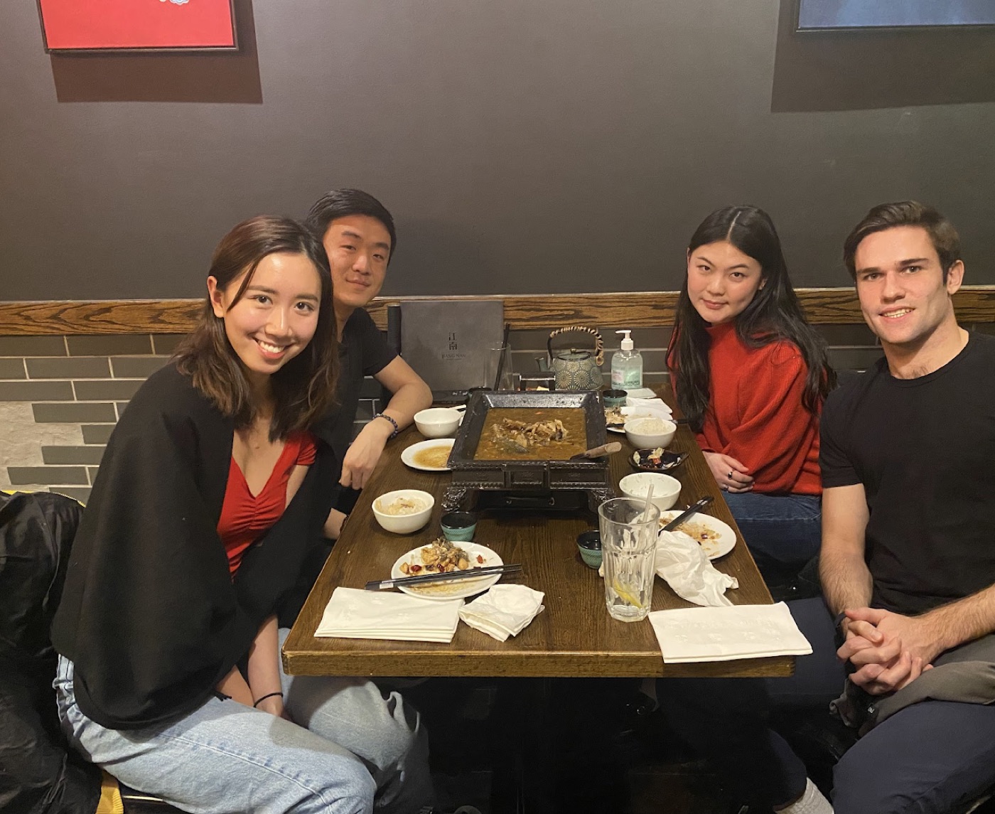 Noel and three friends around a bubbling tabletop hot pot at a casual restaurant, plates nearly finished.